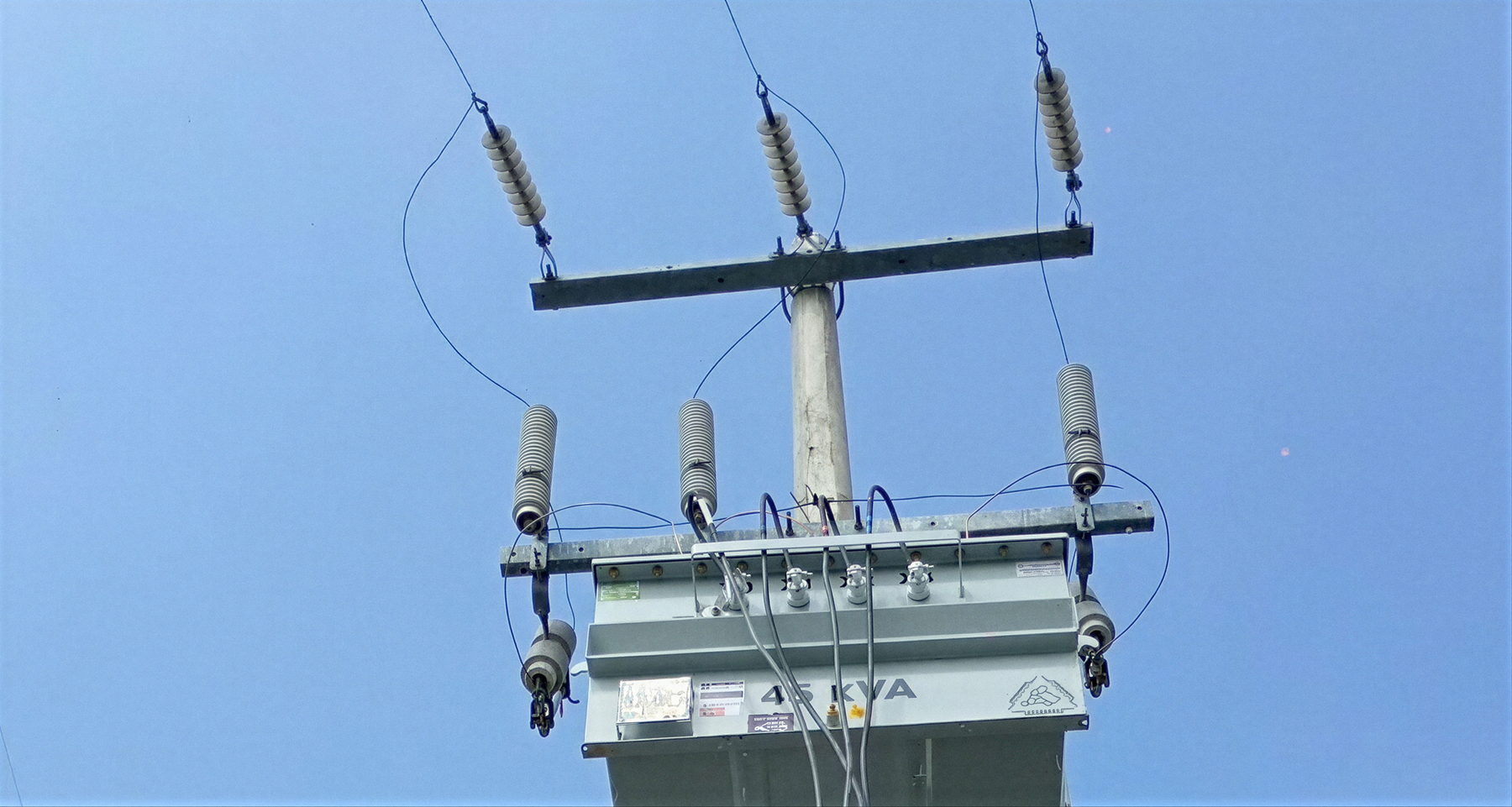 Transformador de 45 kVA montado en poste, con cortacircuitos fusible y apartarrayos conectados a la línea de media tensión